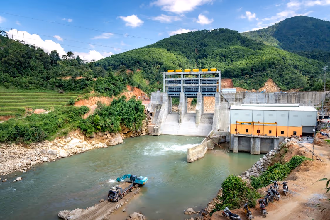 hydroelectric dam in a lush mountainous region under blue skies