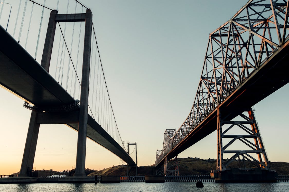side-by-side bridges over a body of water at dusk