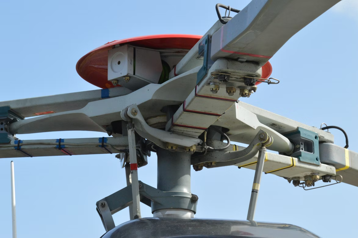 close up of a white and red helicopter rotor flying in blue skies