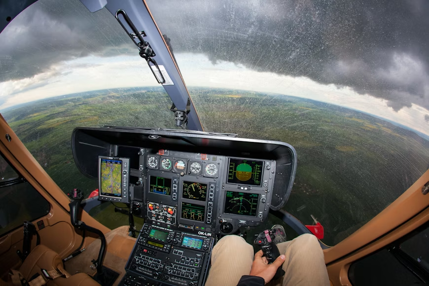 man flying a helicopter over green fields on a rainy day