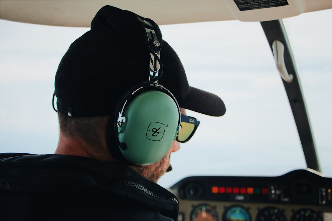 close-up of a pilot in a helicopter cockpit wearing sunglasses and a headset to communicate