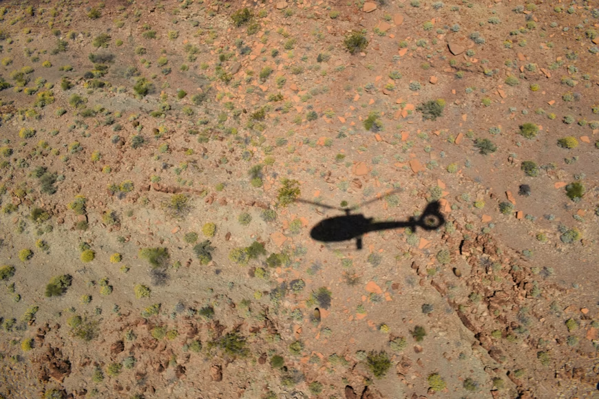 helicopter shadow projected onto desert ground during daytime