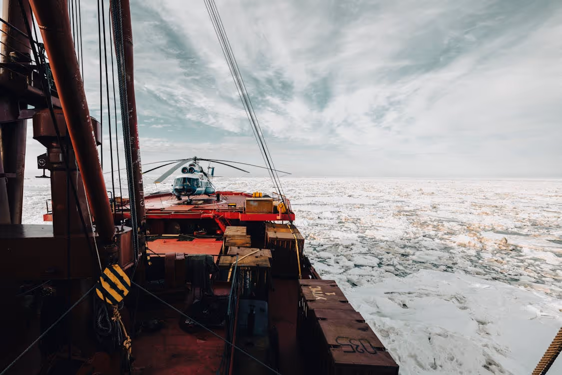 white helicopter resting on an icebreaker in the ice-covered Arctic Ocean