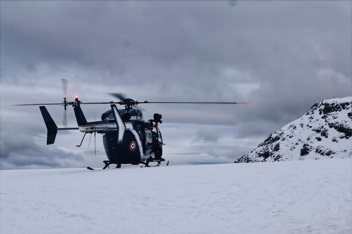 navy and white helicopter resting on snow-covered ground under cloudy skies