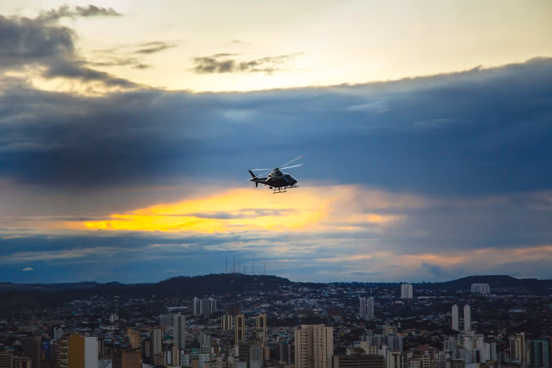 helicopter flying over a dense city at sunset