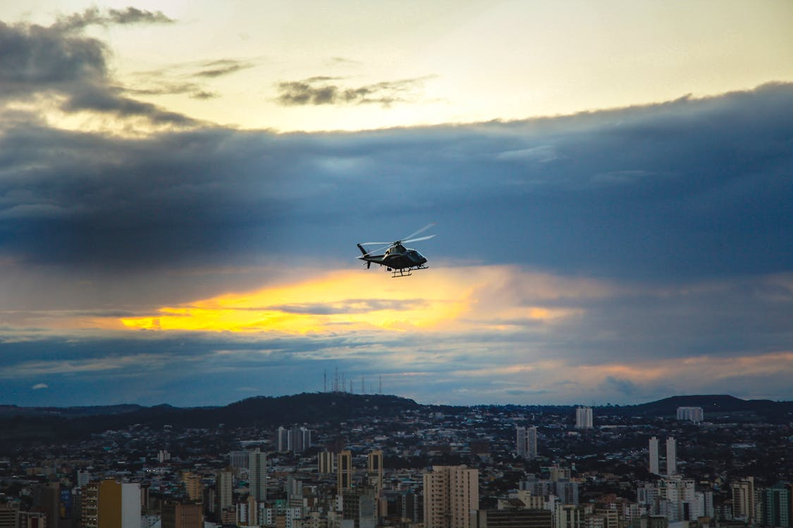 helicopter flying over a dense city at sunset