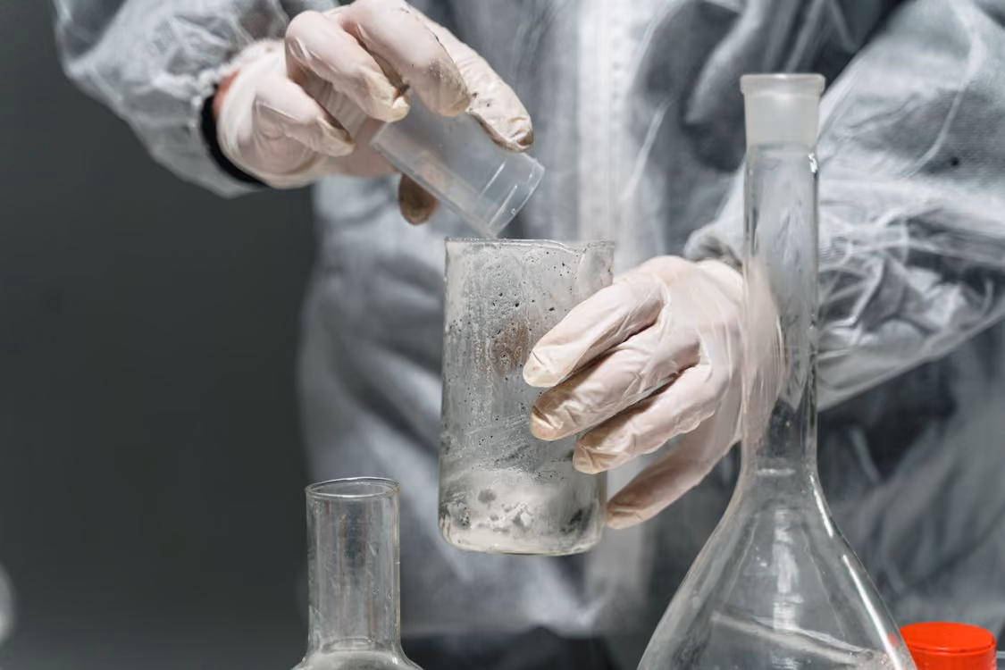 scientist wearing personal protective equipment working with glassware and chemicals in a laboratory setting