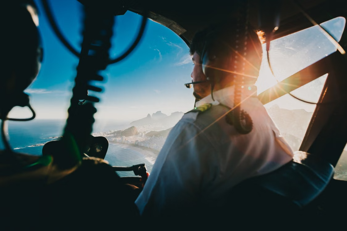 helicopter pilot wearing a headset navigating over Rio de Janeiro at sunset