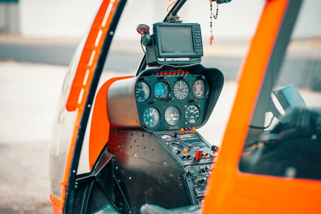 close-up of cockpit display panels, controls, and navigation equipment inside a bright orange helicopter