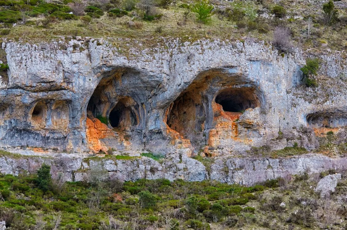 natural caves carved into a rugged grassy cliffside