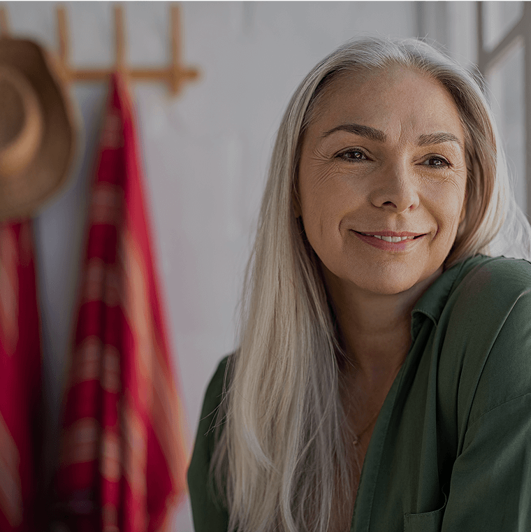 A woman with long grey hair smiling at home