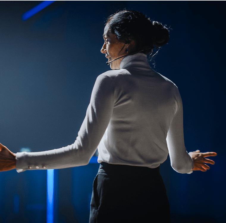 A presenter speaking to an audience on stage