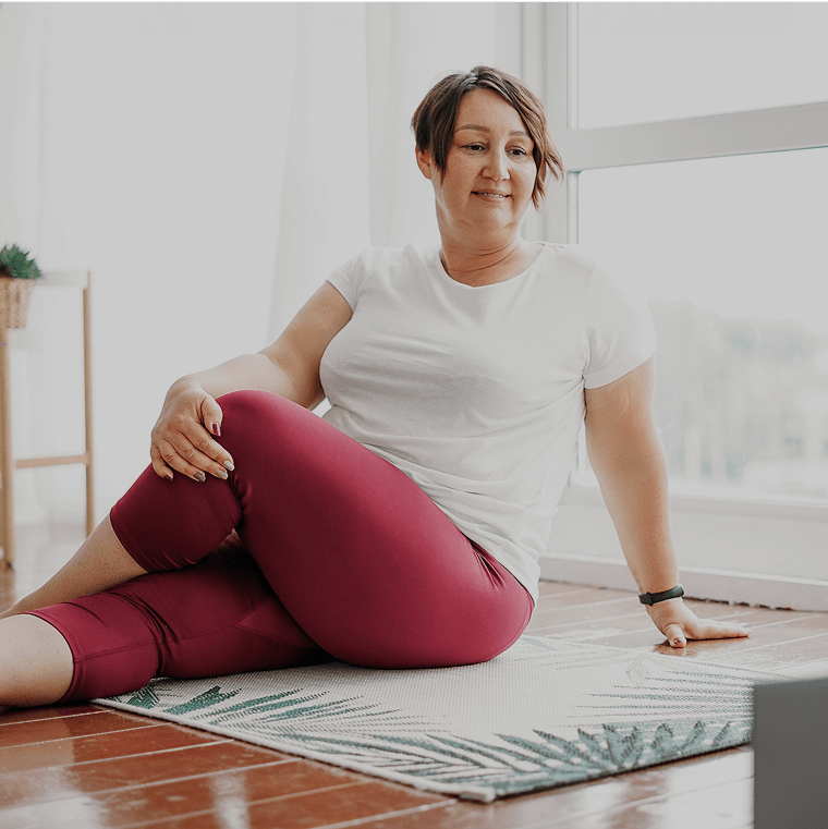 A smiling woman stretching on a mat at home