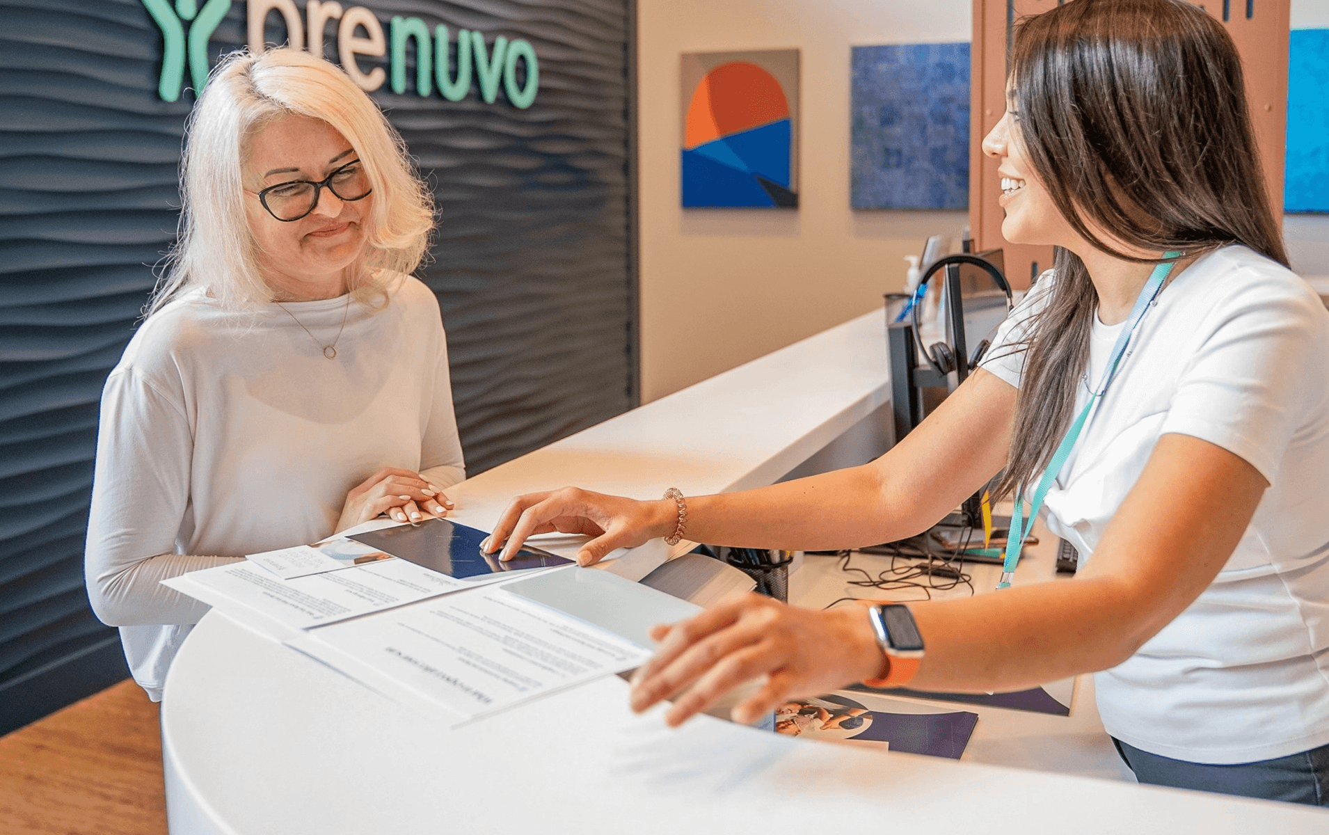 A patient going over paperwork with a staff member at a Prenuvo clinic desk