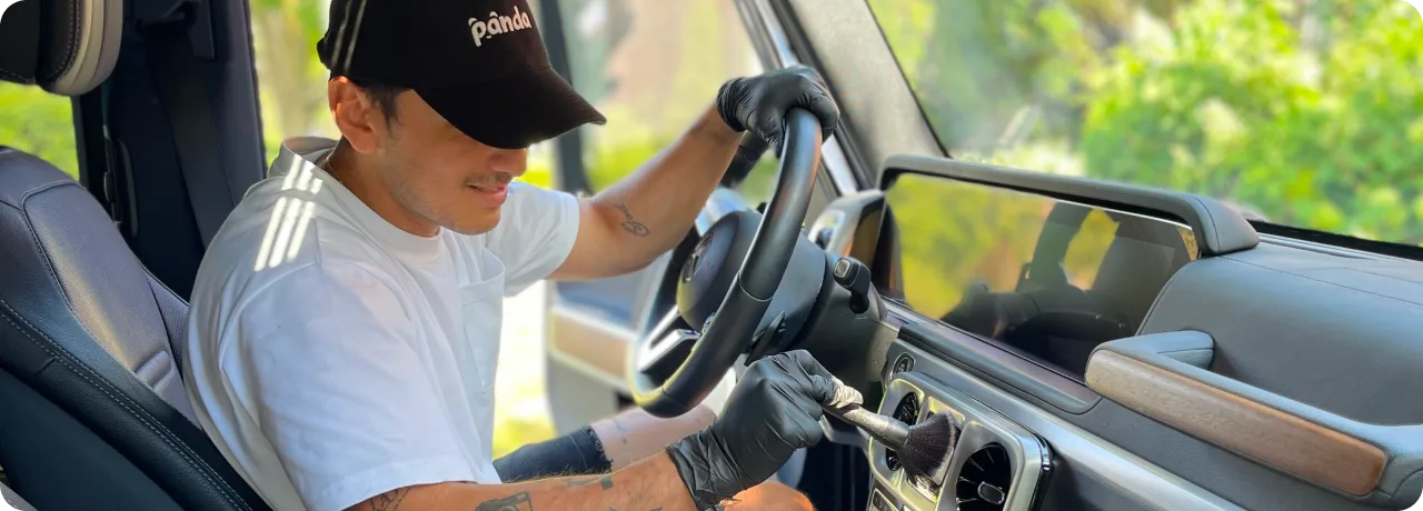 A professional car detailer cleaning the interior air vents of an Audi