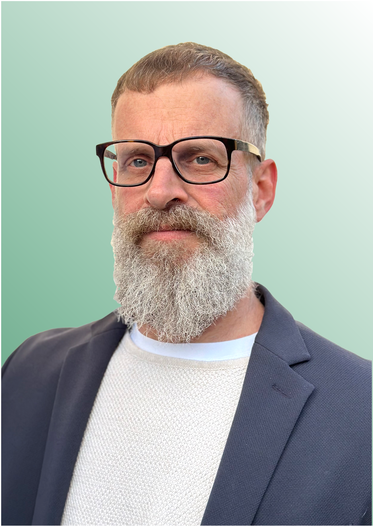 Middle-aged man with gray beard and glasses wearing a dark blazer and white textured sweater on a green gradient background.