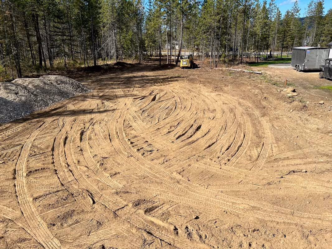 Dirt ground with curved tire tracks in forest construction site