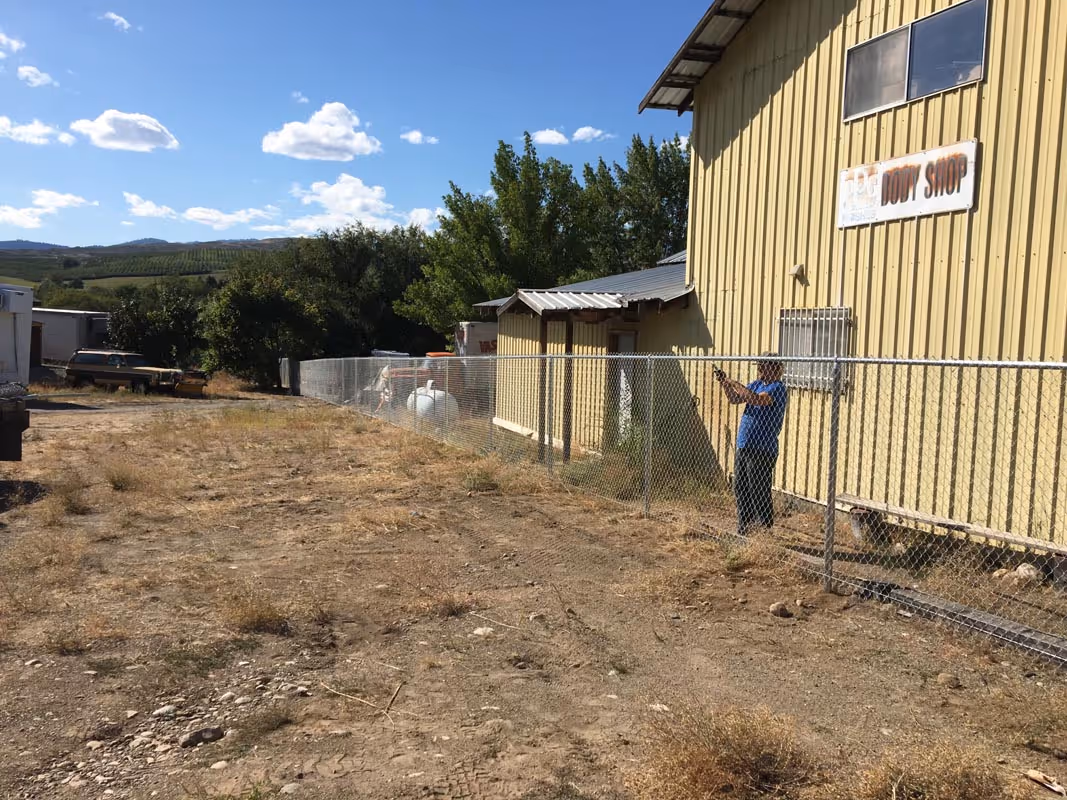 Yellow building with Dairy Shop sign and chain-link fence on dry landscape