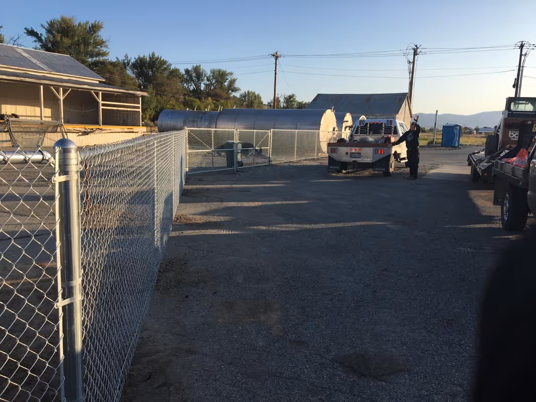 Fenced industrial yard with truck, utility buildings, and power lines