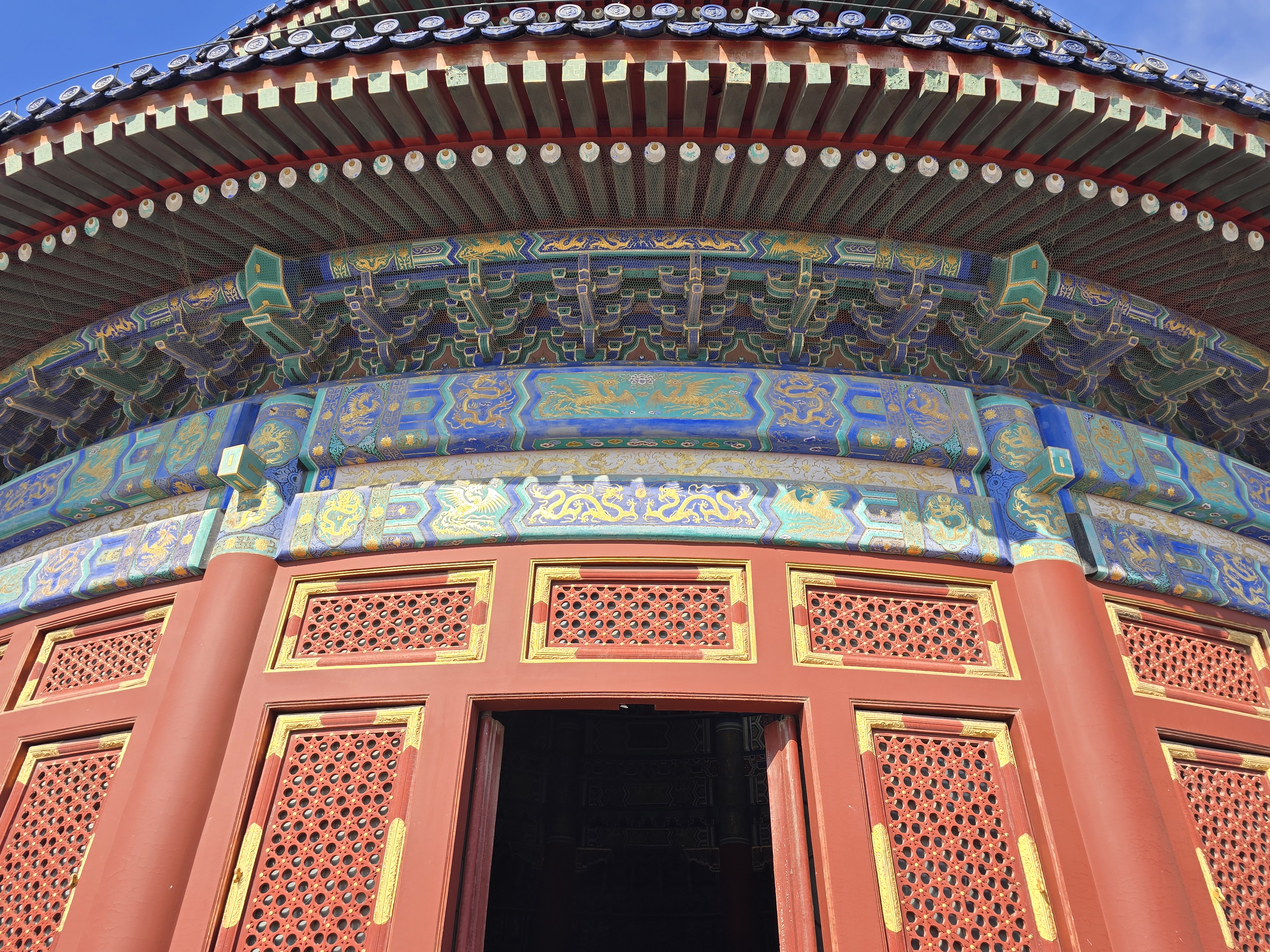 Red doors and painted beams beneath the hall’s blue-tiled eaves.