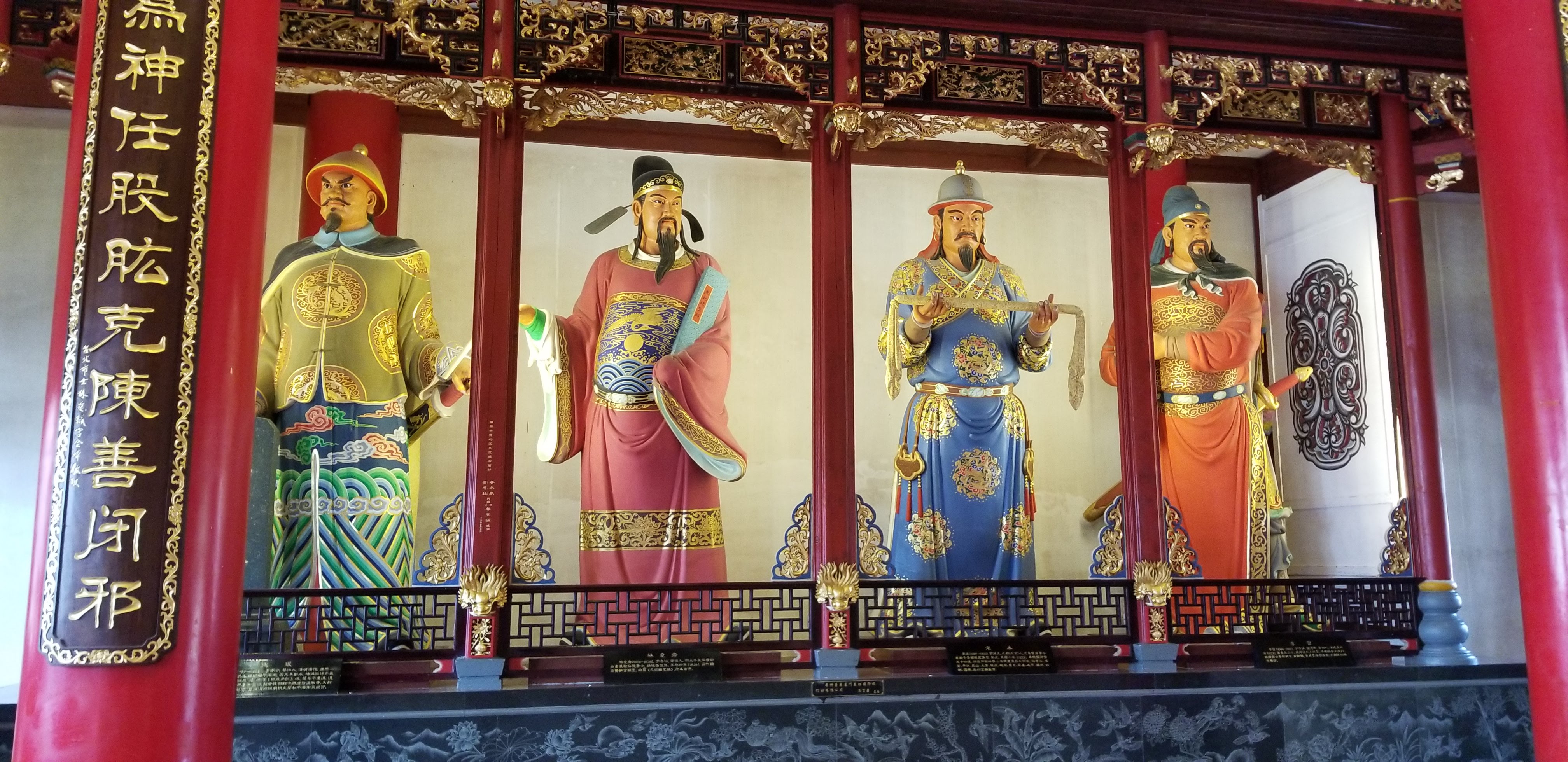 Four richly painted figures inside a temple hall