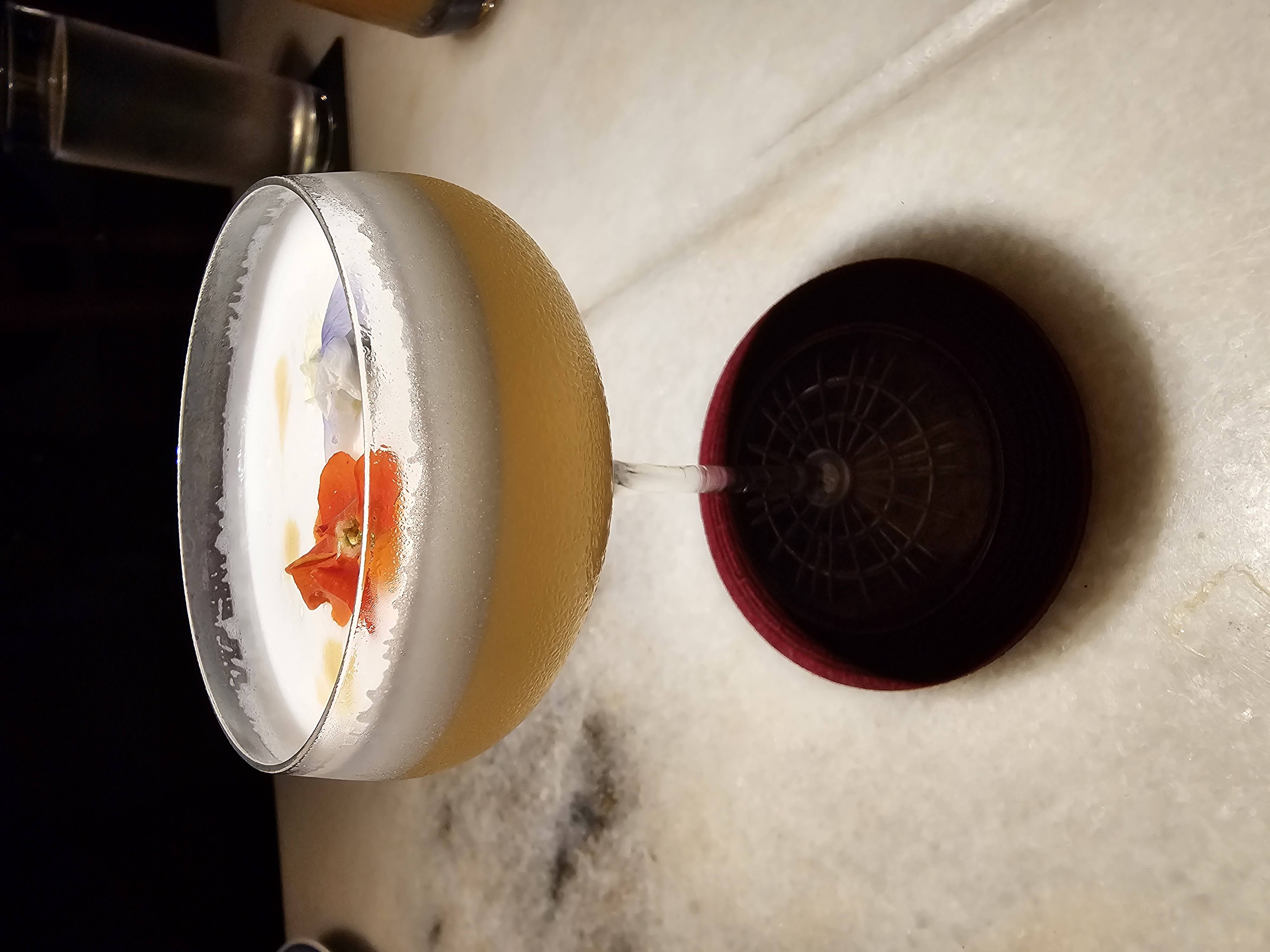Foam-topped cocktail in a coupe glass with a red garnish