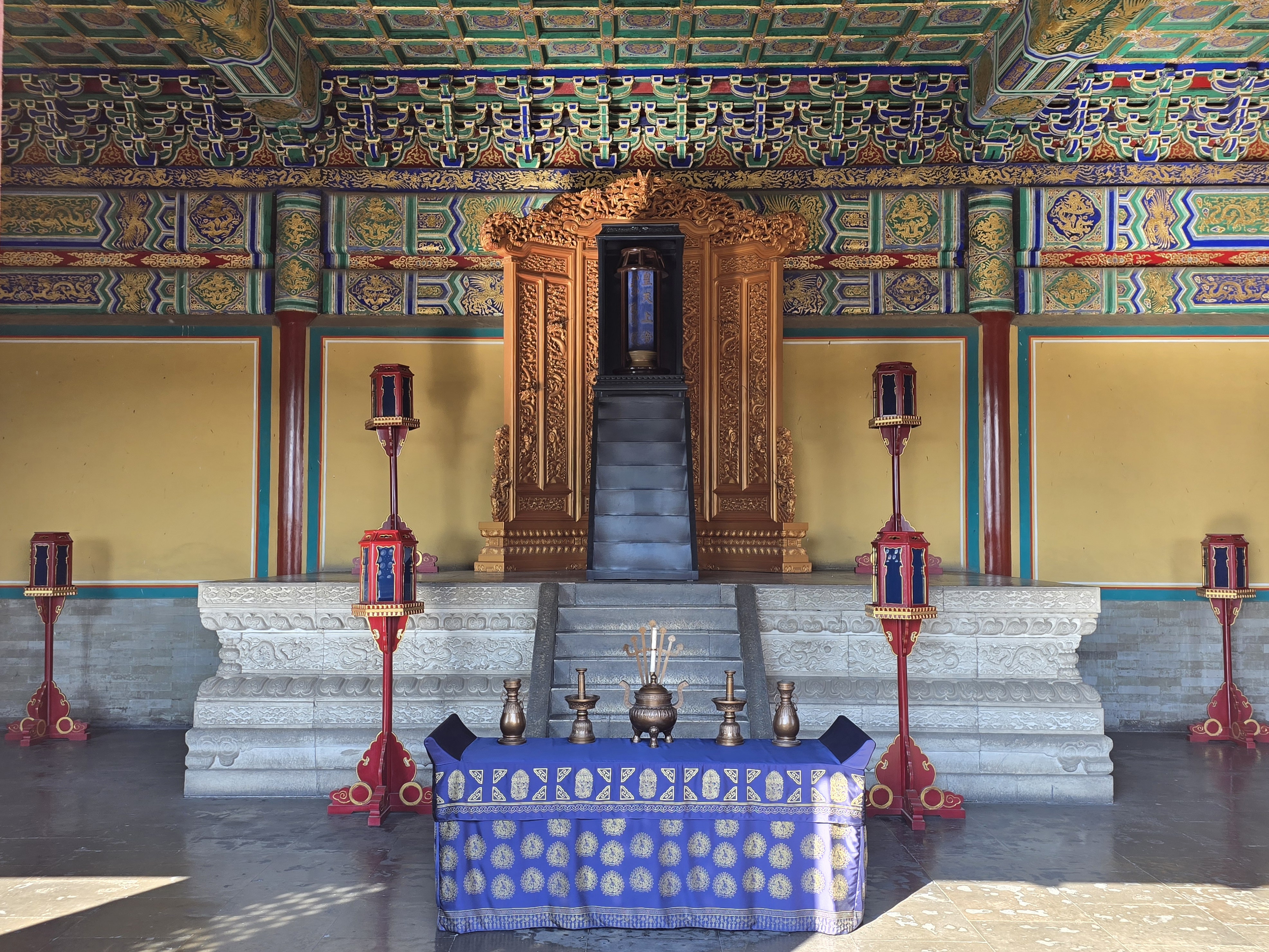 An altar display beneath dense painted ceiling decoration.