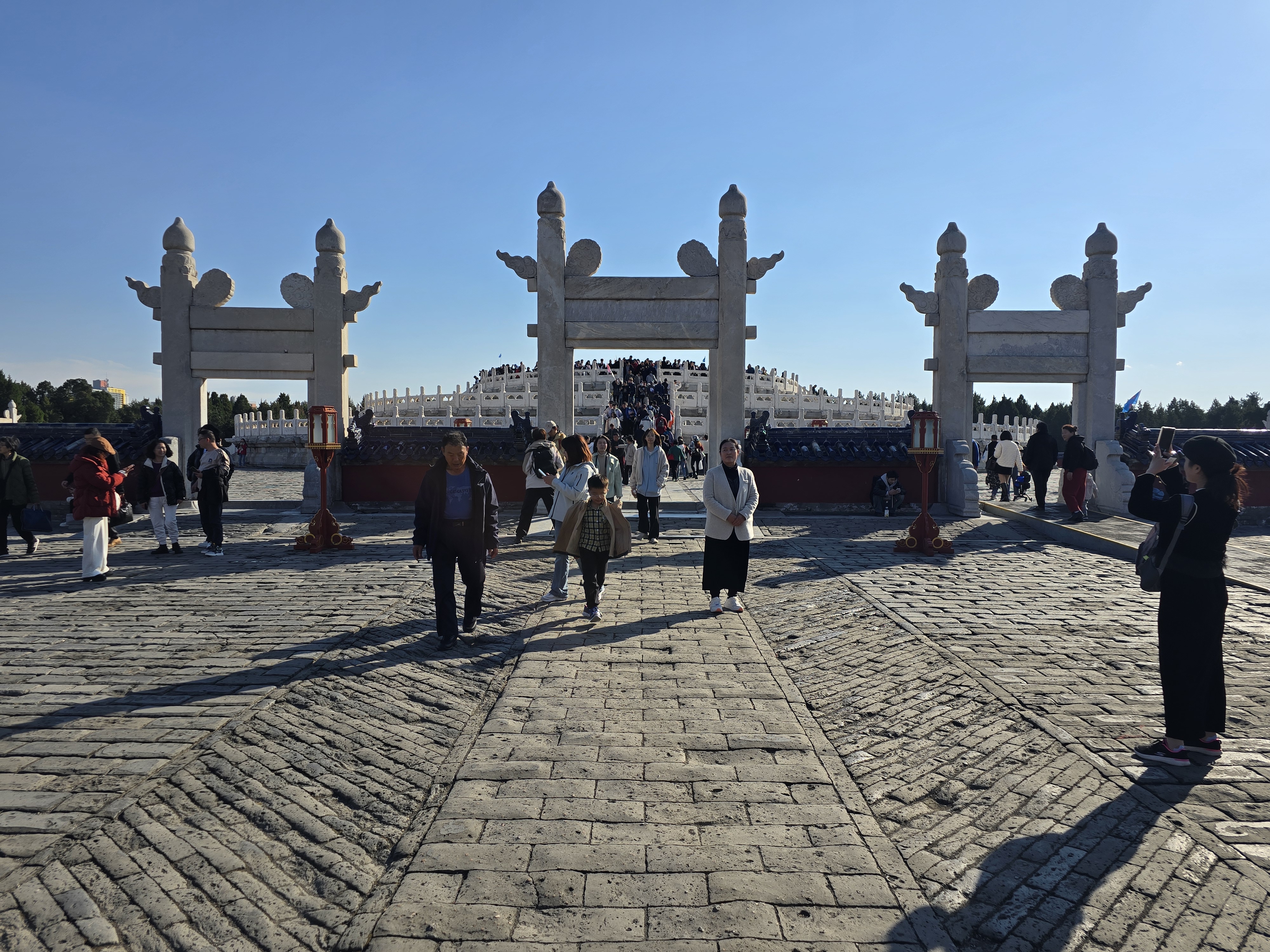 Stone archways stand in silhouette beyond the temple visitors.