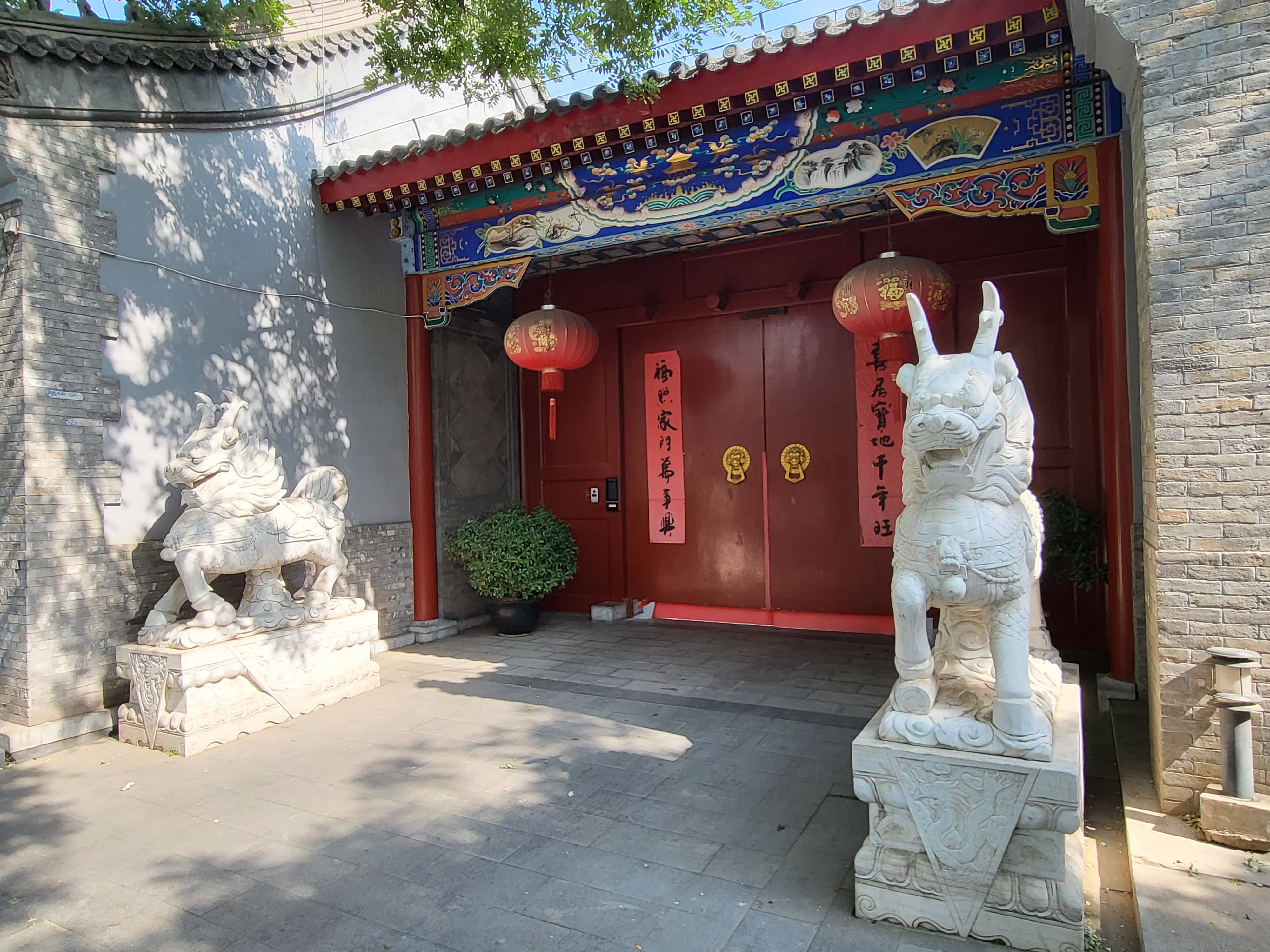 A red doorway guarded by pale stone animals.