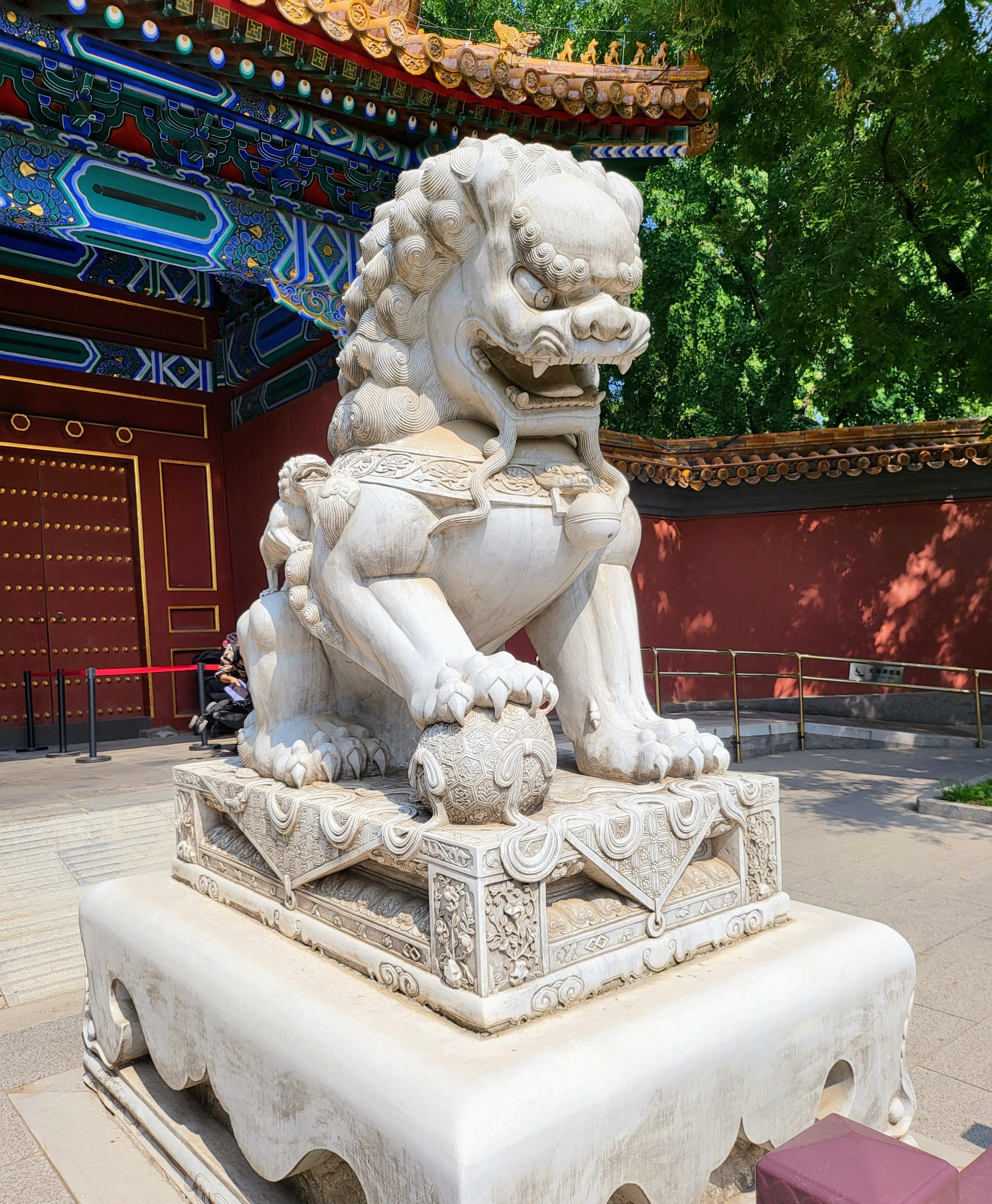 A stone guardian lion on its carved pedestal.