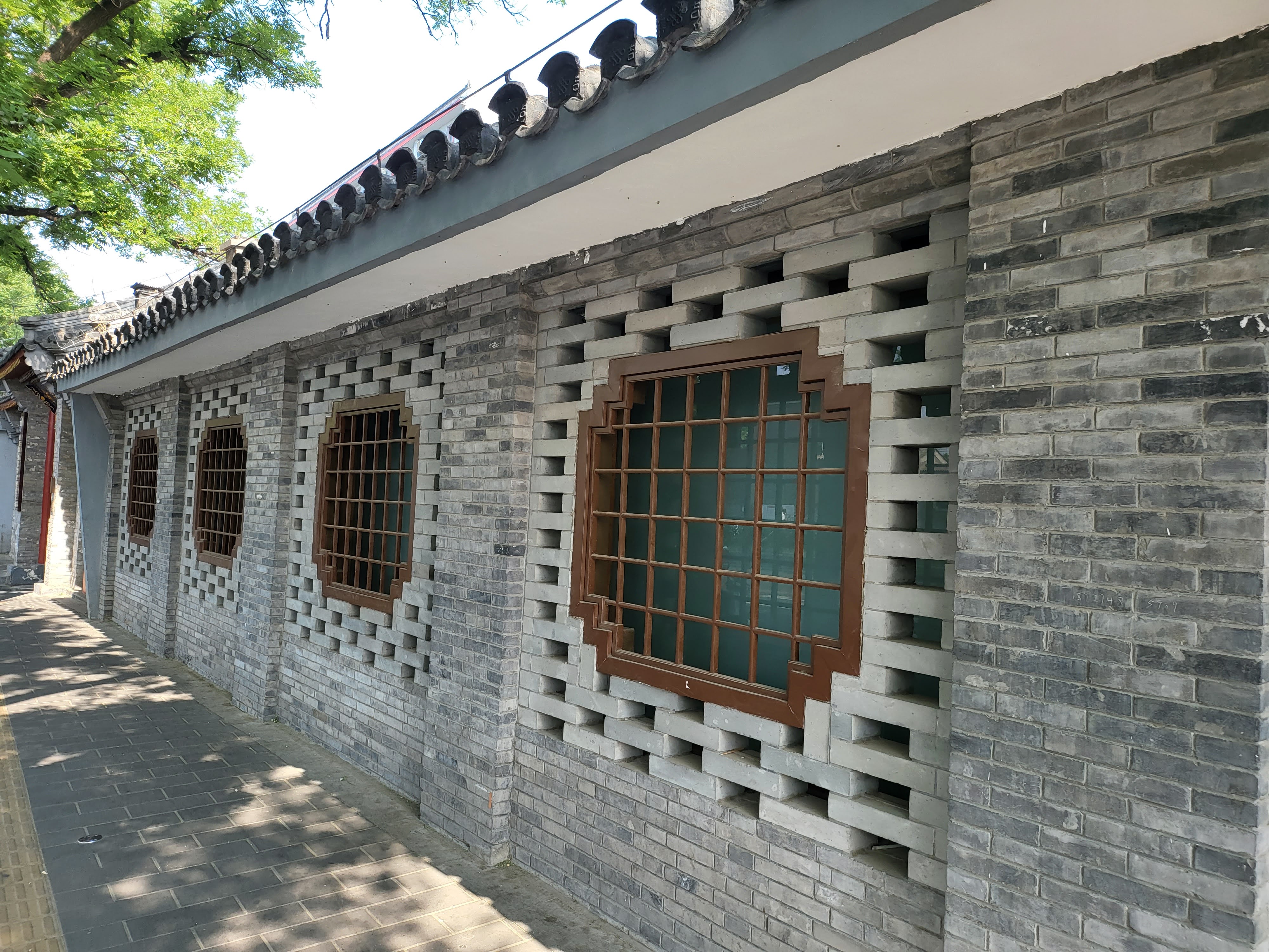 Grey-brick courtyard houses along a shaded lane.