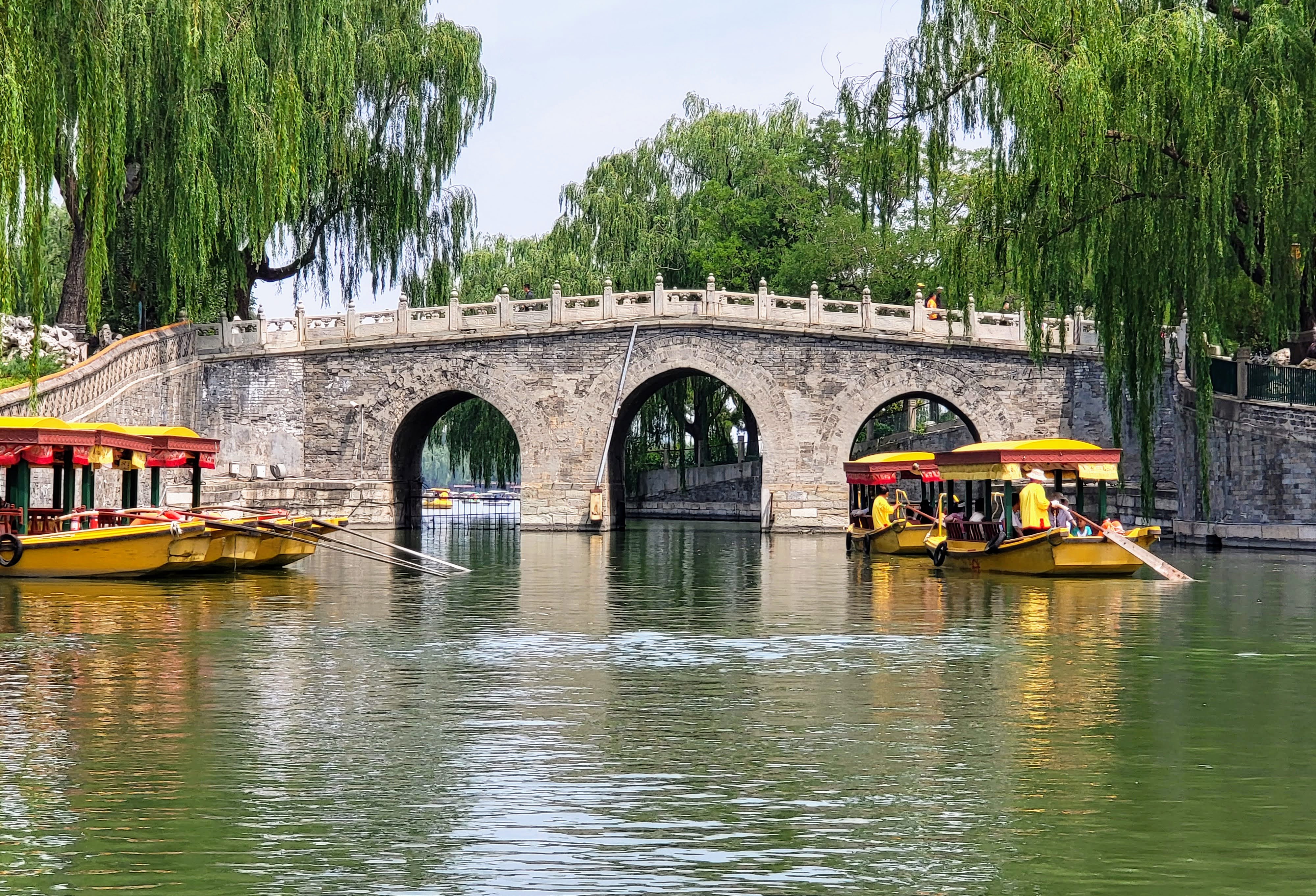 An arched stone bridge beneath hanging willows.