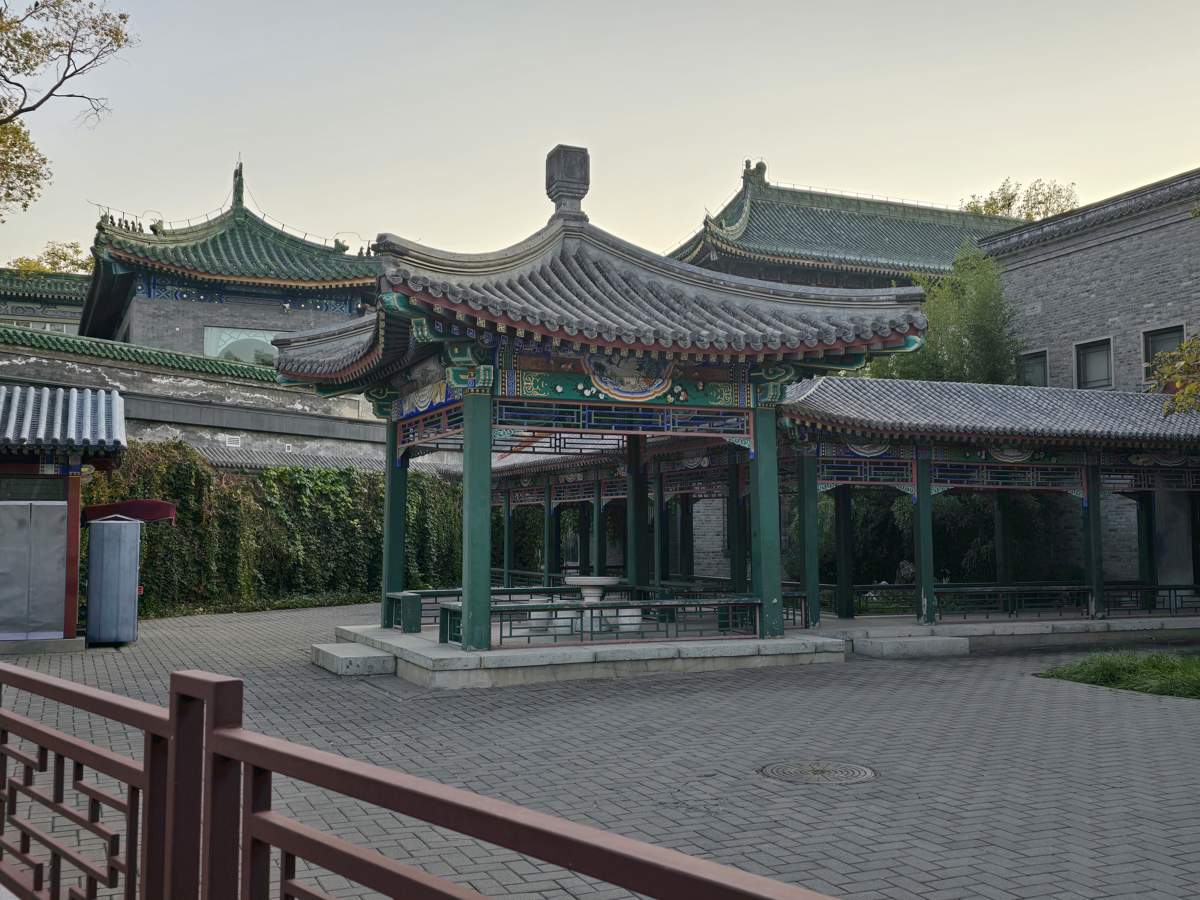 Green-roofed buildings beside a quiet paved courtyard.