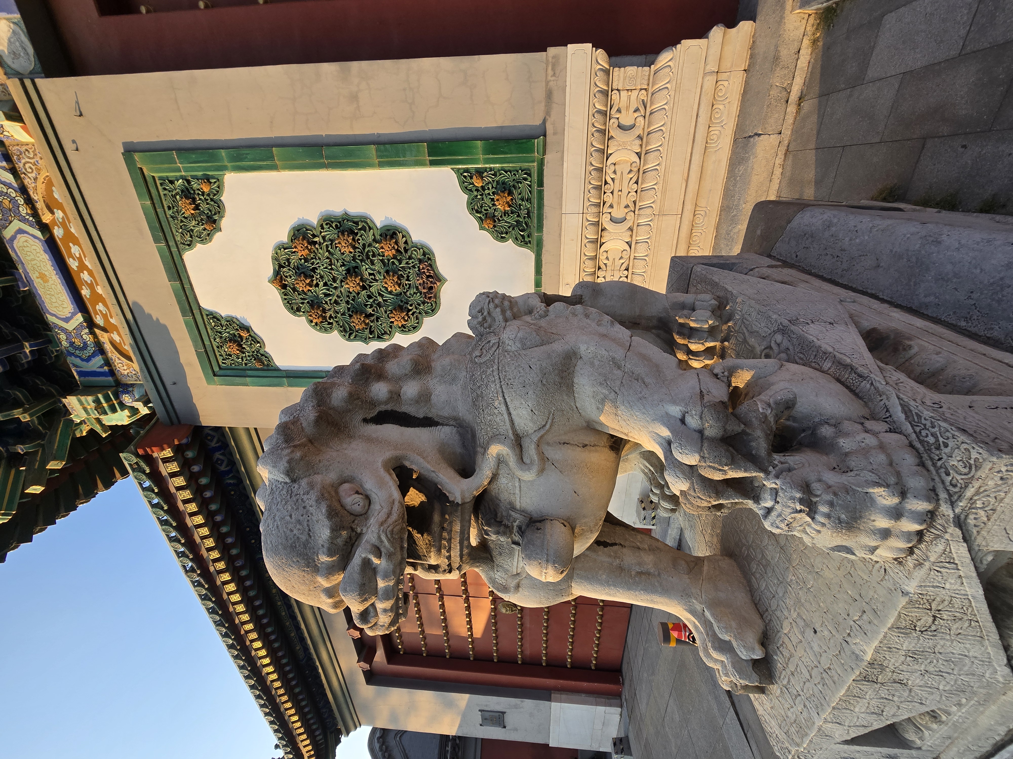 A stone guardian lion beside a decorated entrance.