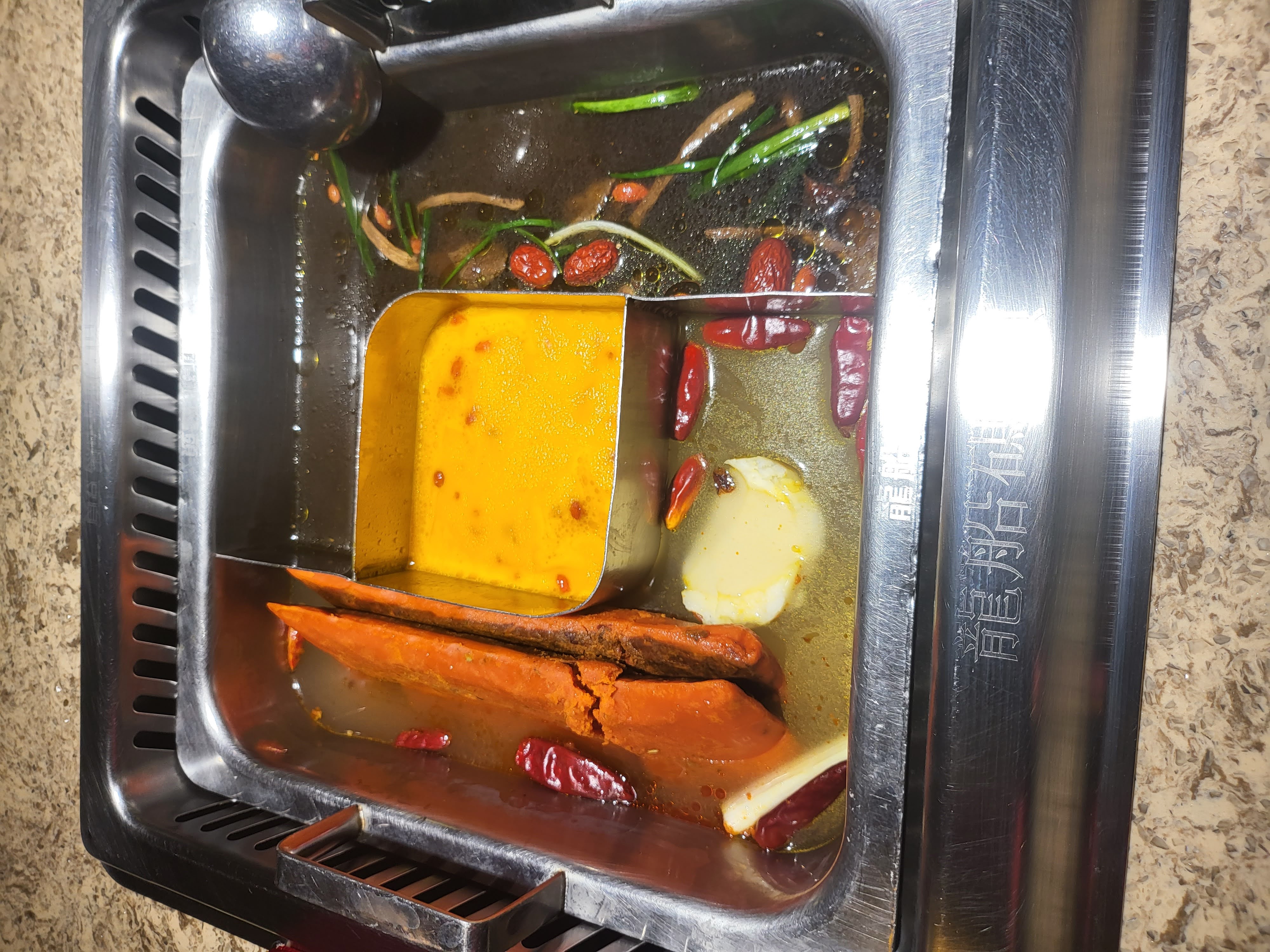 A divided hot pot holds contrasting broths for the meal.