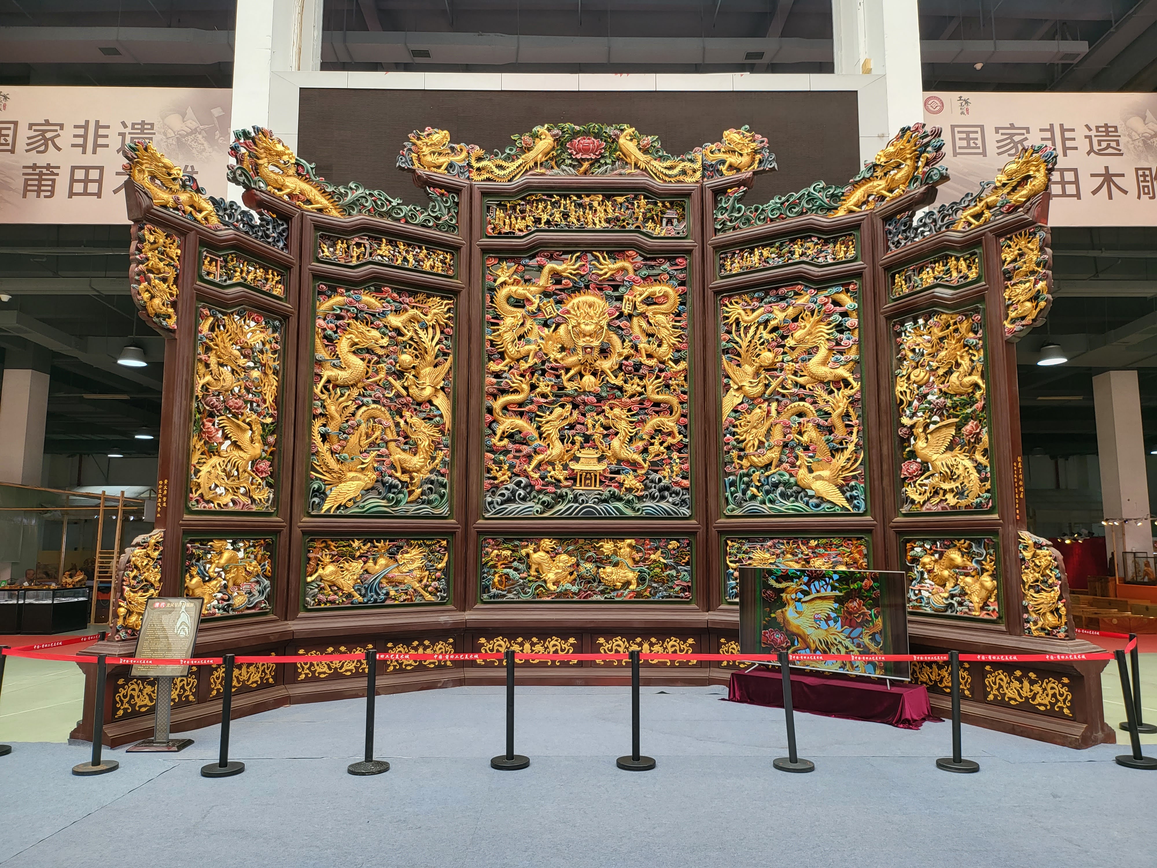 A gilded folding screen filled with dragons and ornament.