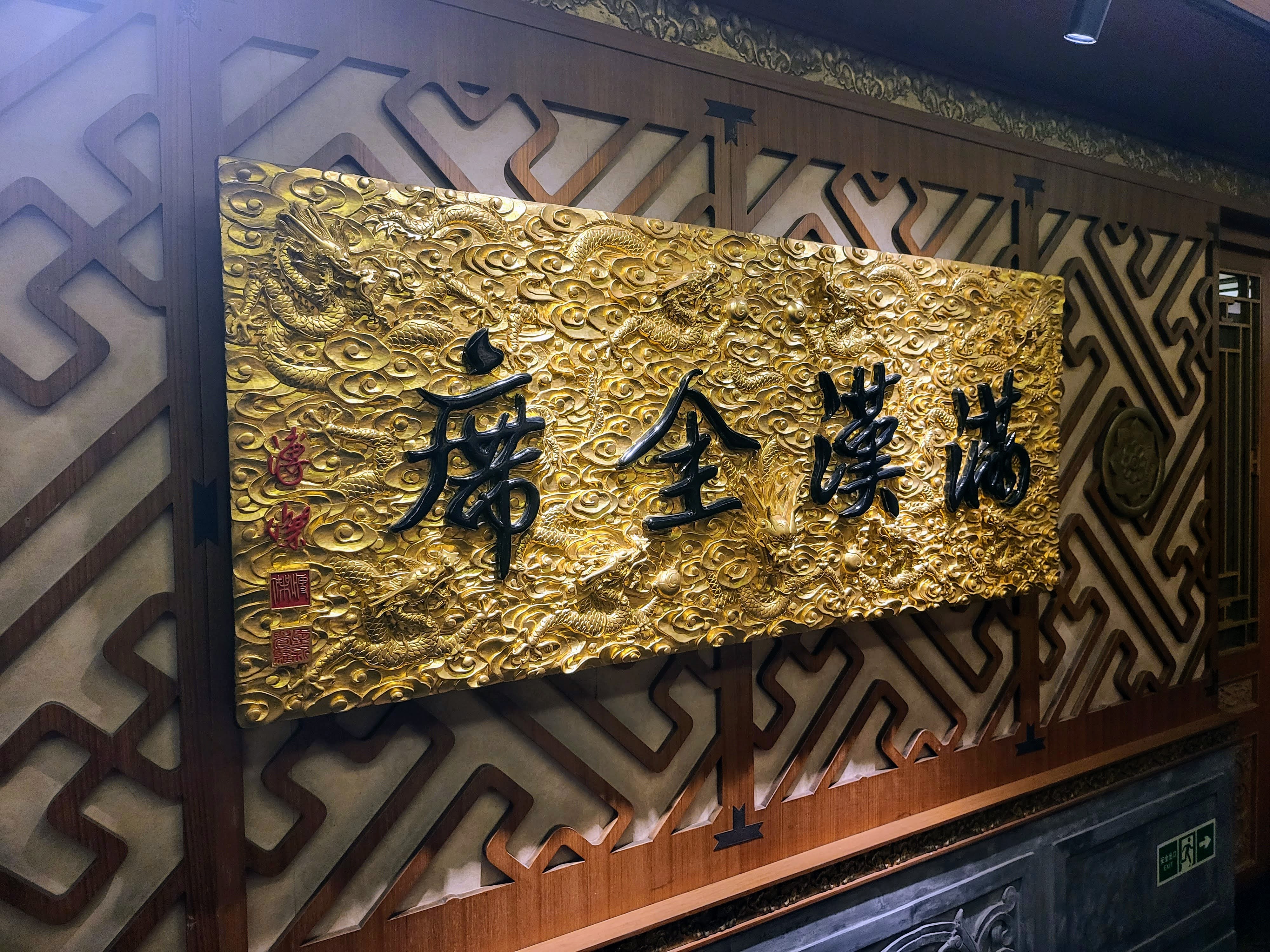 A gold-lettered plaque surrounded by carved decoration.