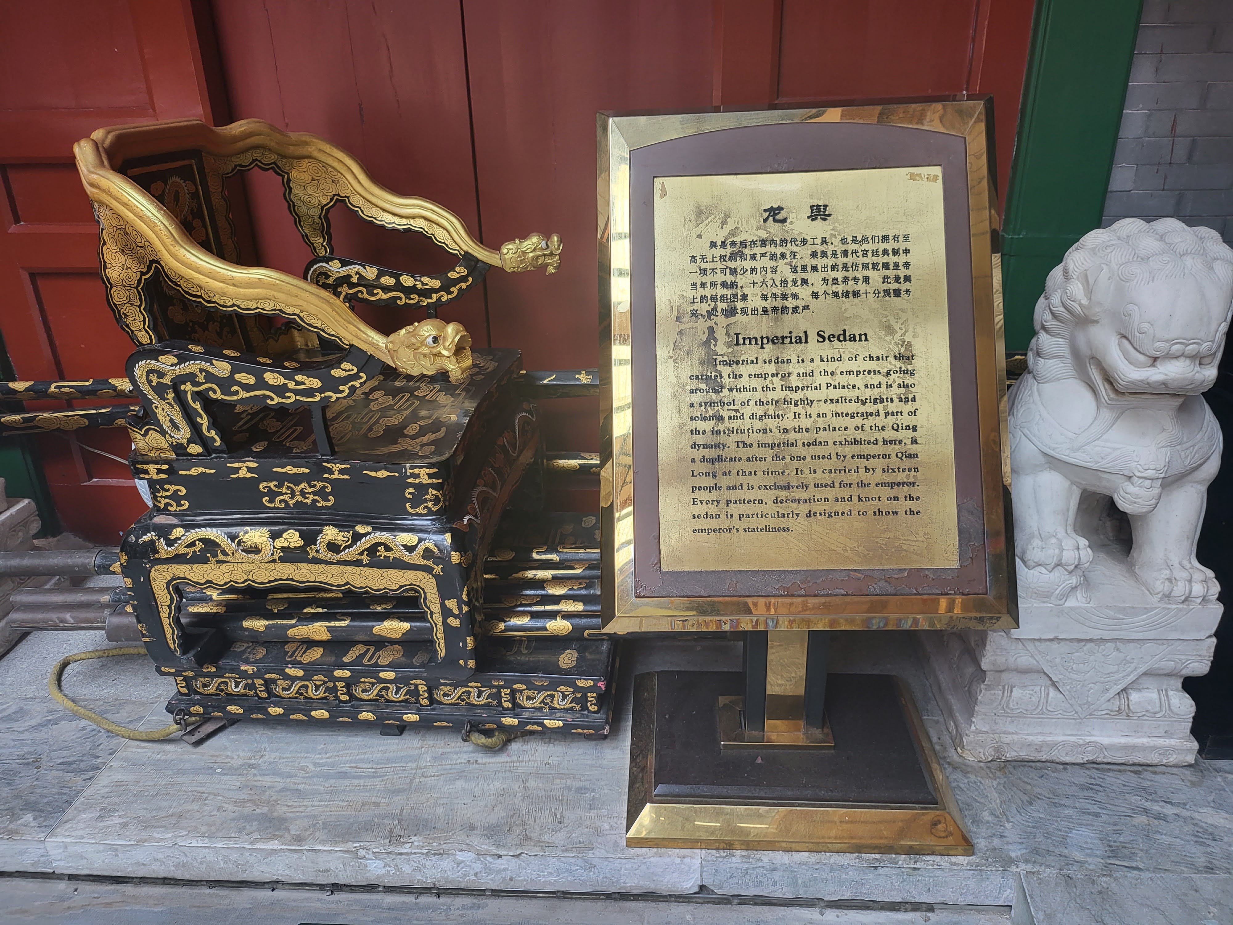 A ceremonial seat displayed beside an explanatory plaque.