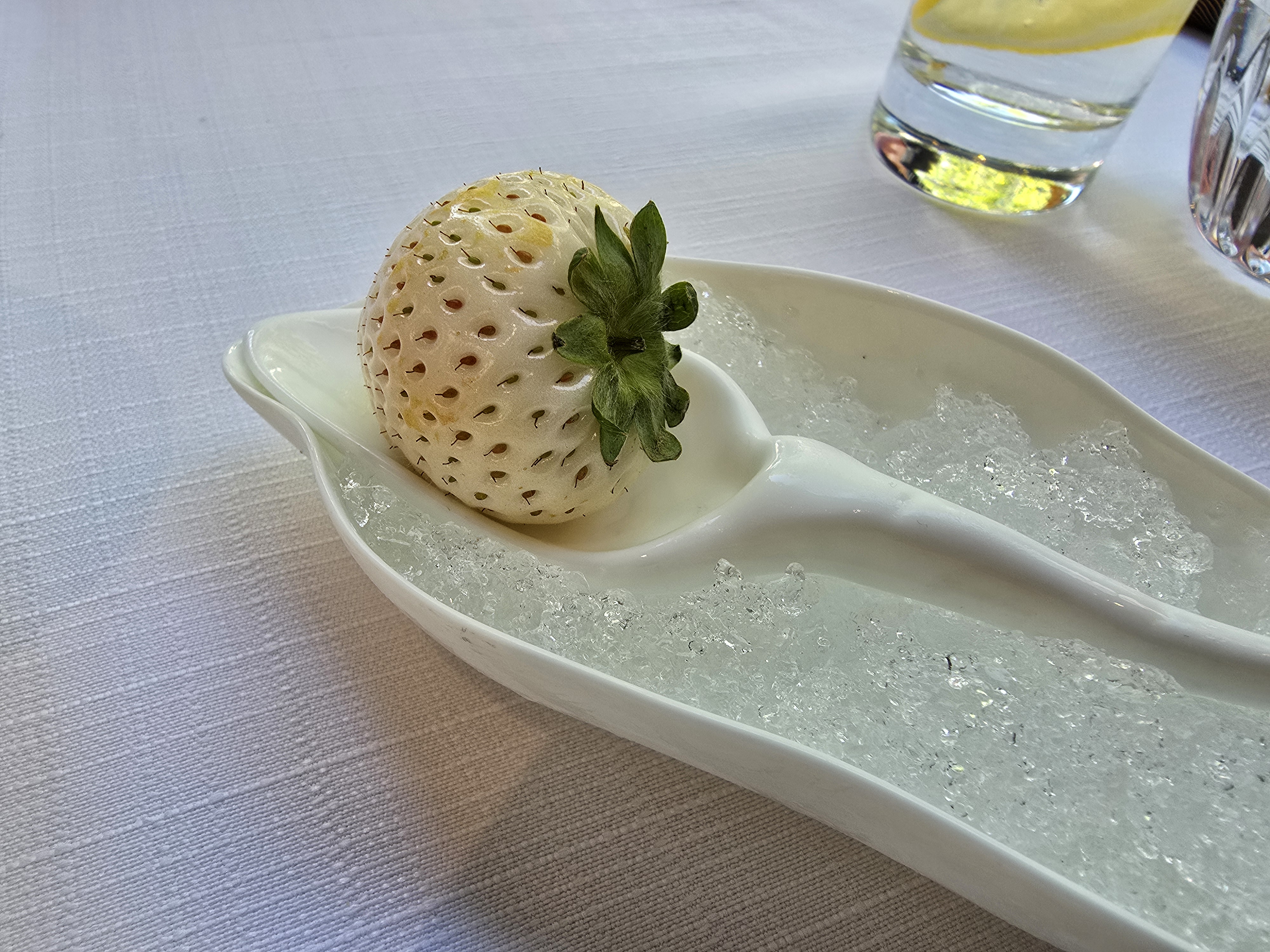A white strawberry presented on a spoon.