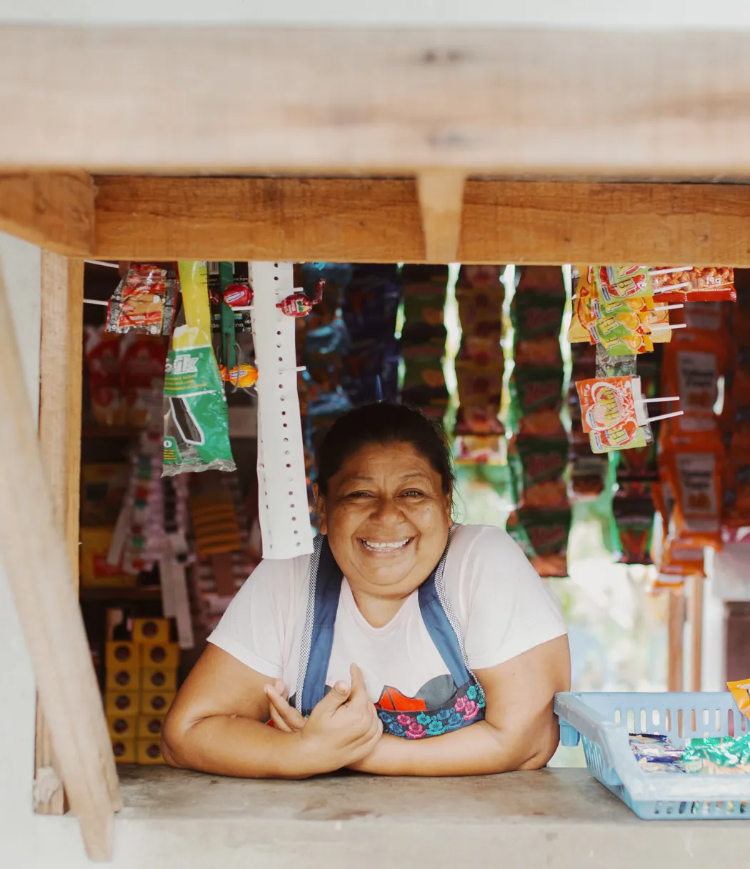 A woman smiling behind the counter of the shop that she owns