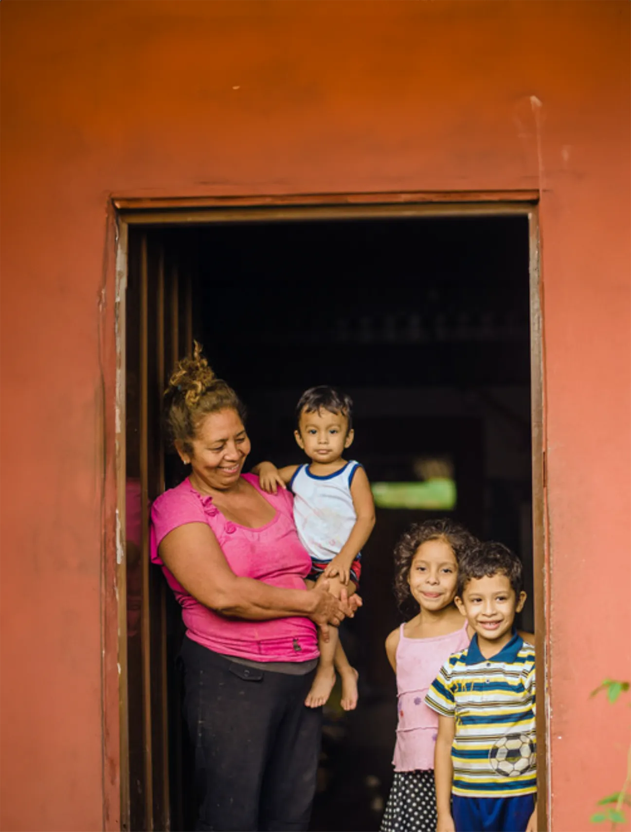 A mother and her children standing in the doorway of their home