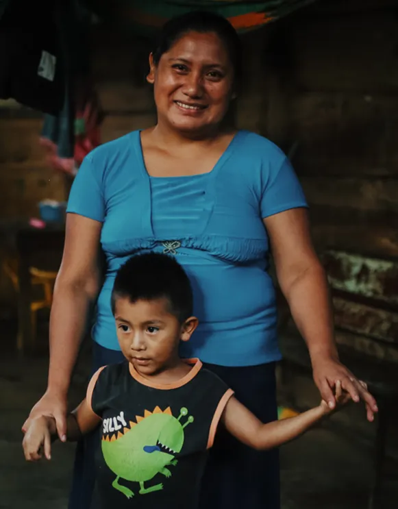 Woman in a blue shirt standing behind her son wearing a black shirt with a cartoon dinosaur on the front