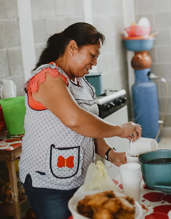 Woman in a white and black polka dotted shirt preparing food