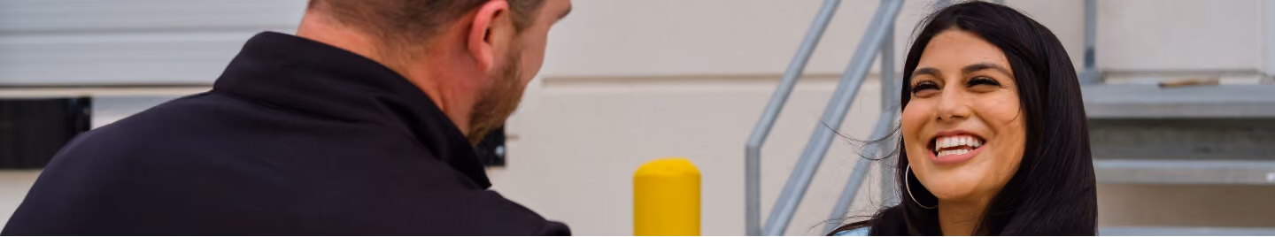 Smiling woman talking with a colleague outside a building
