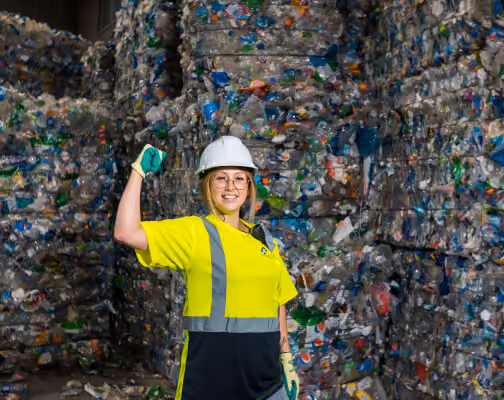 Recycling worker in front of baled plastic bottles