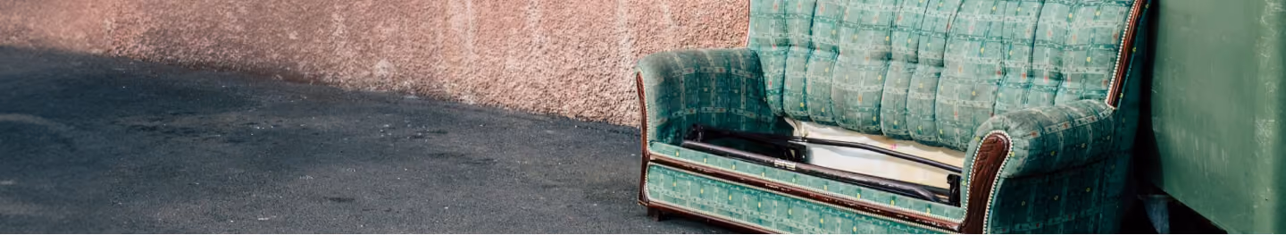 Old green couch left at the curb for bulk pickup