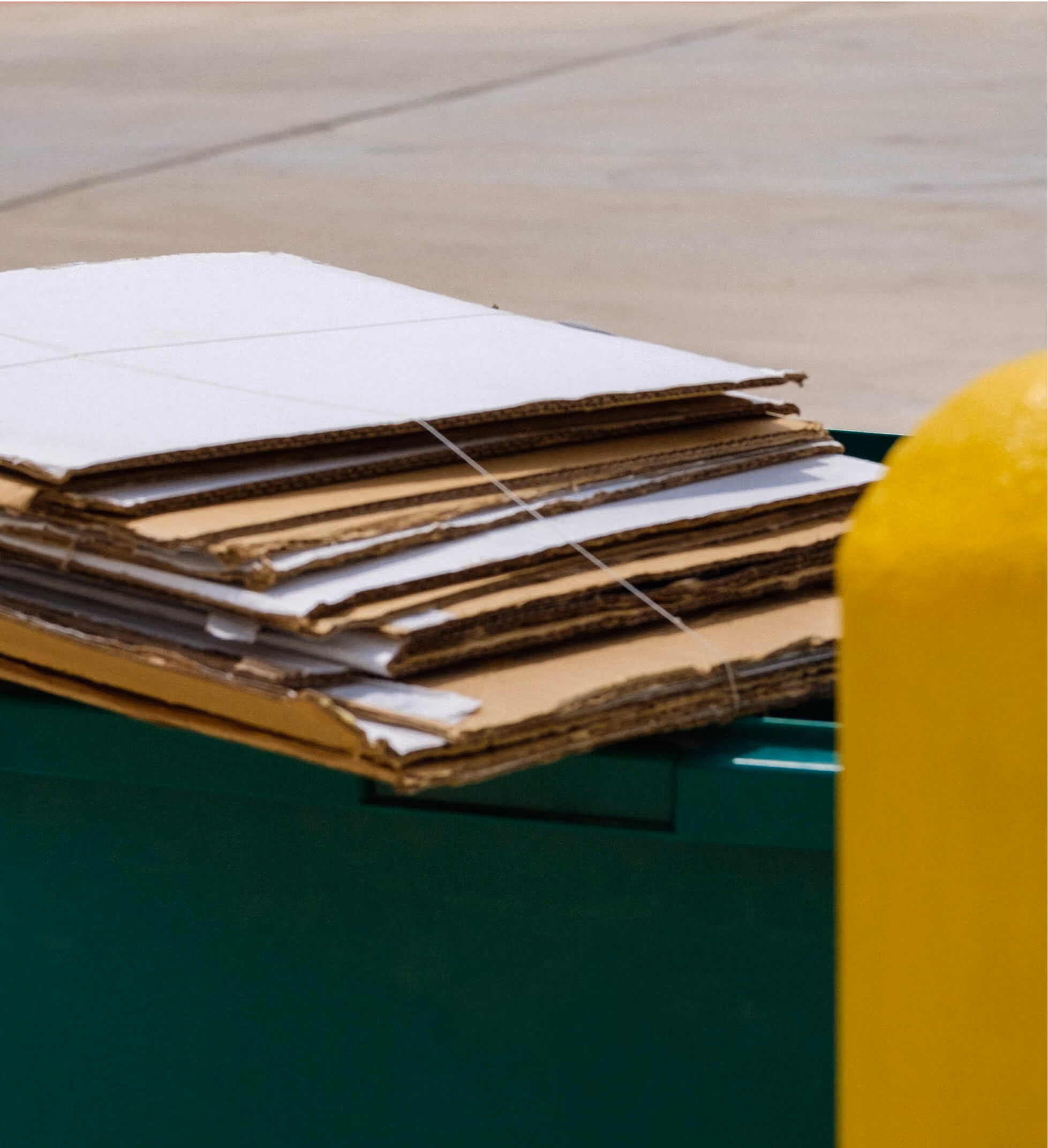 Flattened cardboard stacked on a commercial recycling dumpster