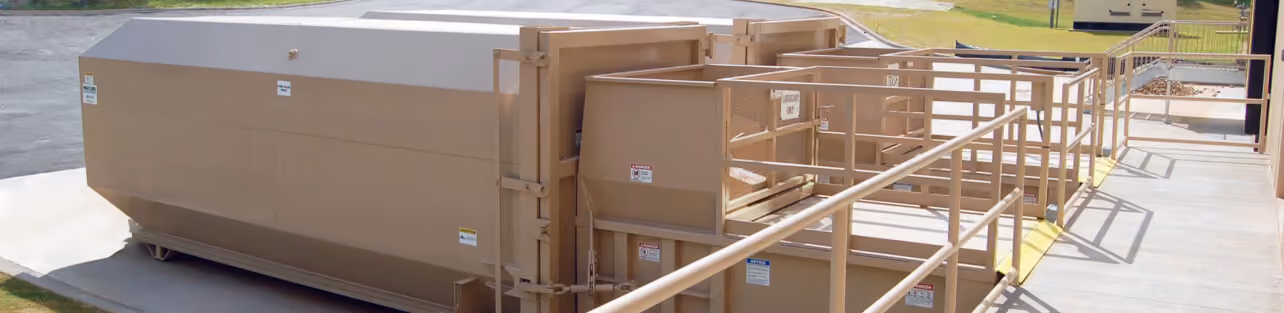 Row of industrial trash compactors outside a building