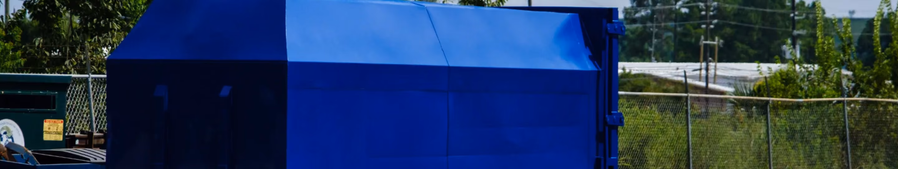 Blue industrial trash compactor outdoors