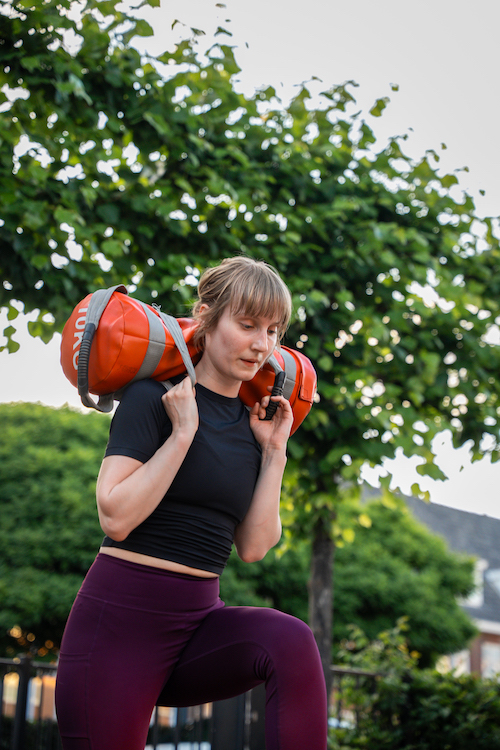 Vrouw doet sandbag lunges tijdens de bootcamp